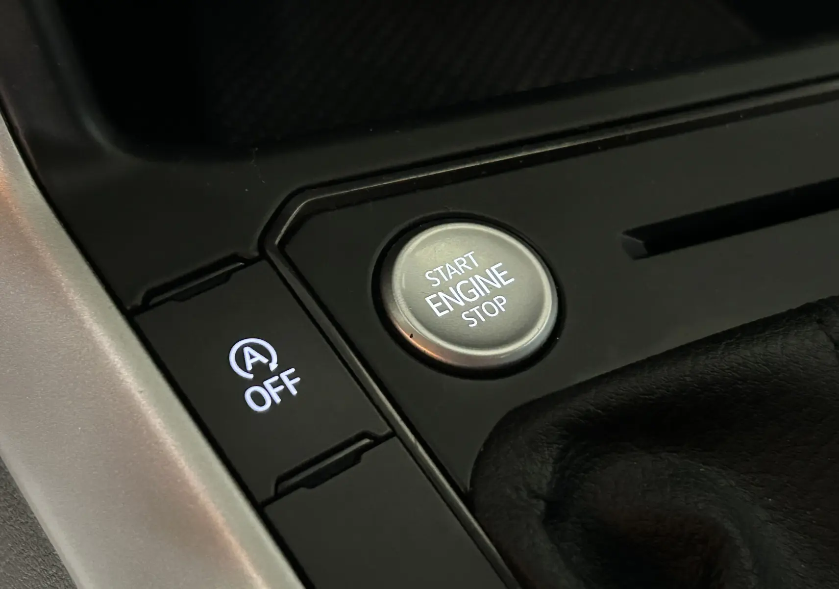 Gros plan sur le bouton Start Engine Stop et la commande d'arrêt du système auto start/stop dans l'habitacle noir d'une Volkswagen Polo.