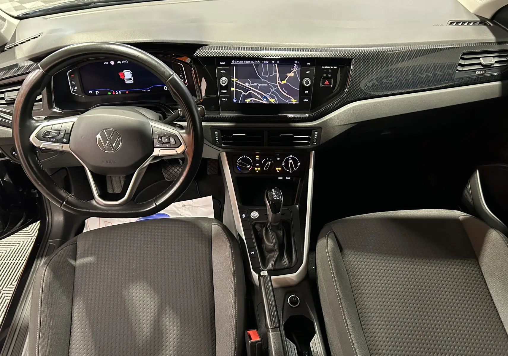 Vue intérieure avant de la Volkswagen Polo noire 2022, mettant en valeur le volant multifonction, l'écran tactile GPS et la console centrale.