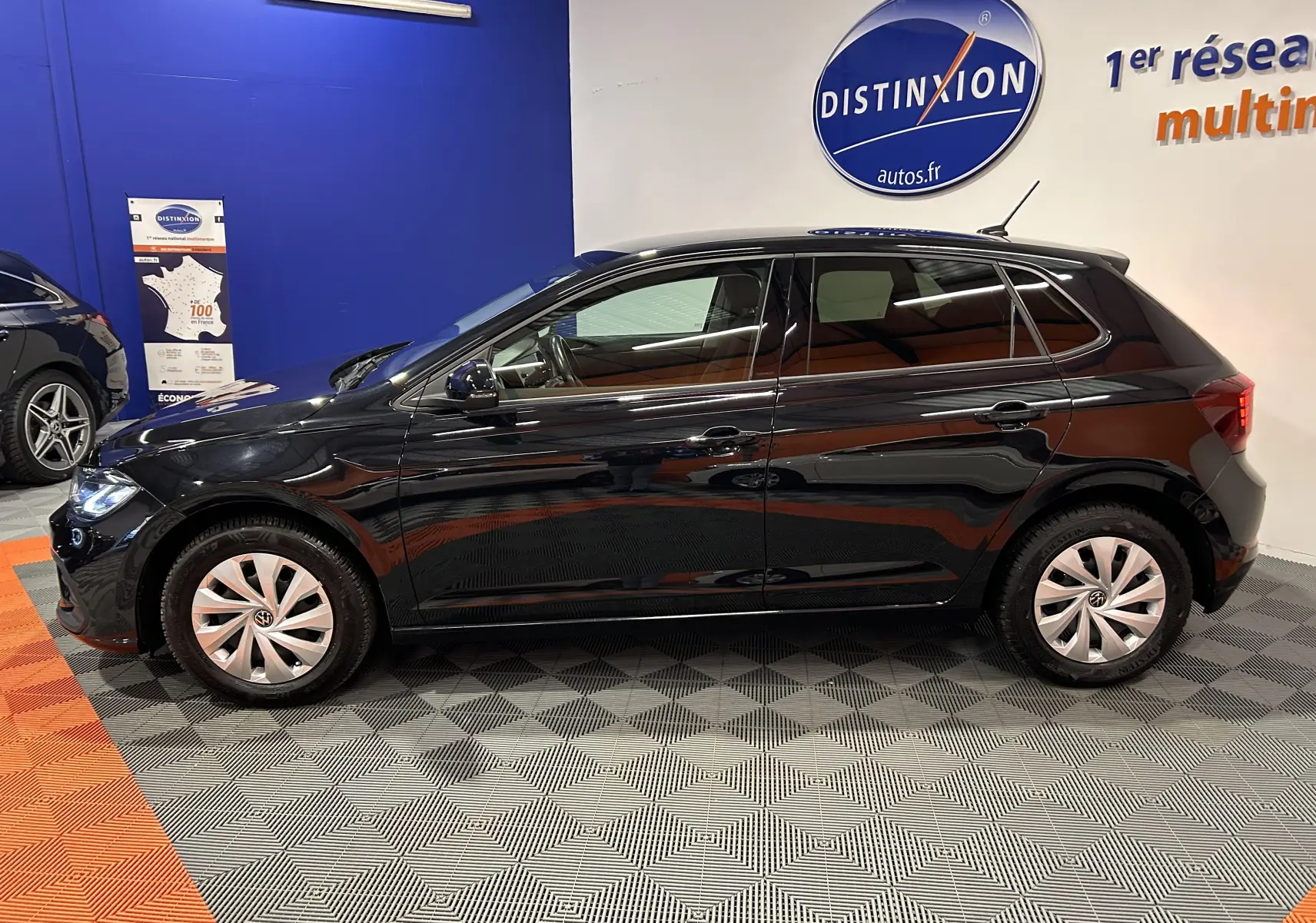 Profil droit d'une Volkswagen Polo noire 2022, avec jantes en alliage et vitres teintées, en intérieur showroom.