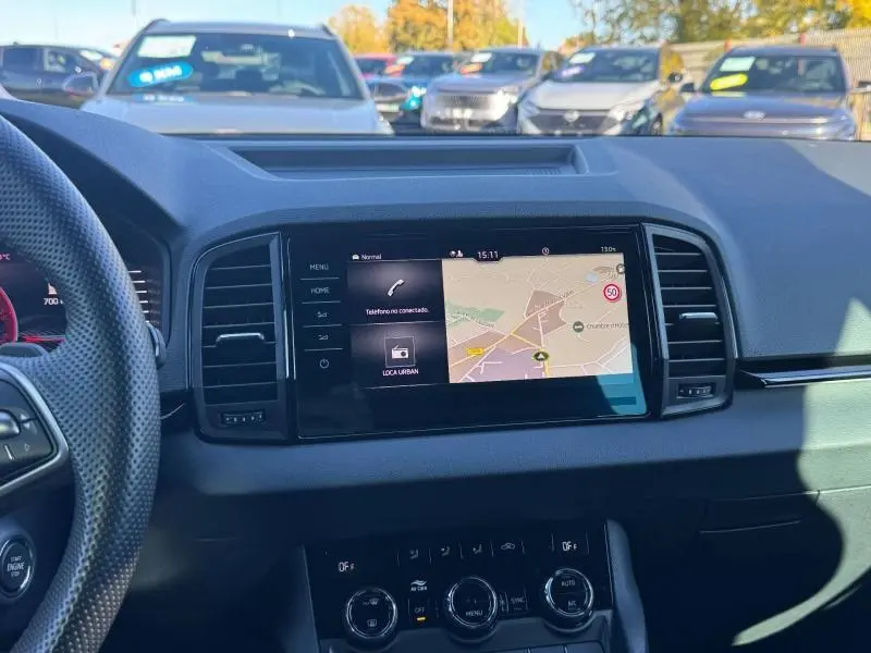 Vue intérieure du tableau de bord du Skoda Karoq gris 2025, avec écran tactile GPS et commandes climatisation visibles.