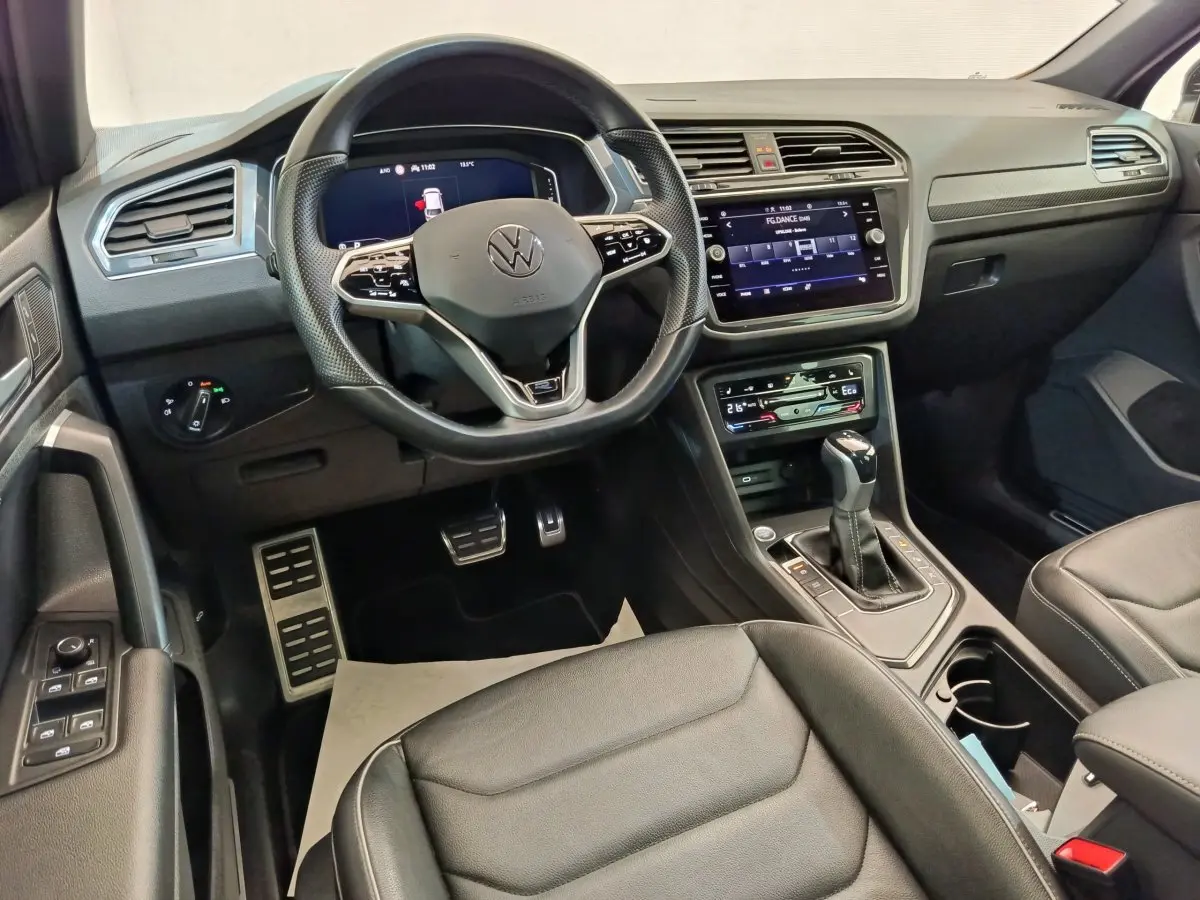 Intérieur noir du Volkswagen Tiguan 1.4 eHybrid 2023, vue côté conducteur sur volant multifonctions et écran tactile central.