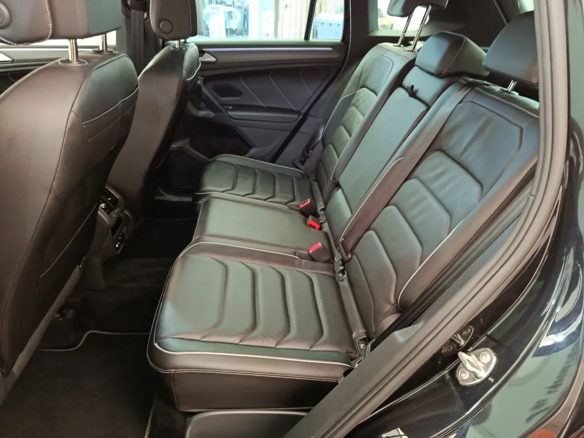 Vue côté droit des sièges arrière en cuir noir du Volkswagen Tiguan 1.4 eHybrid 2023 avec ceinture de sécurité visible.