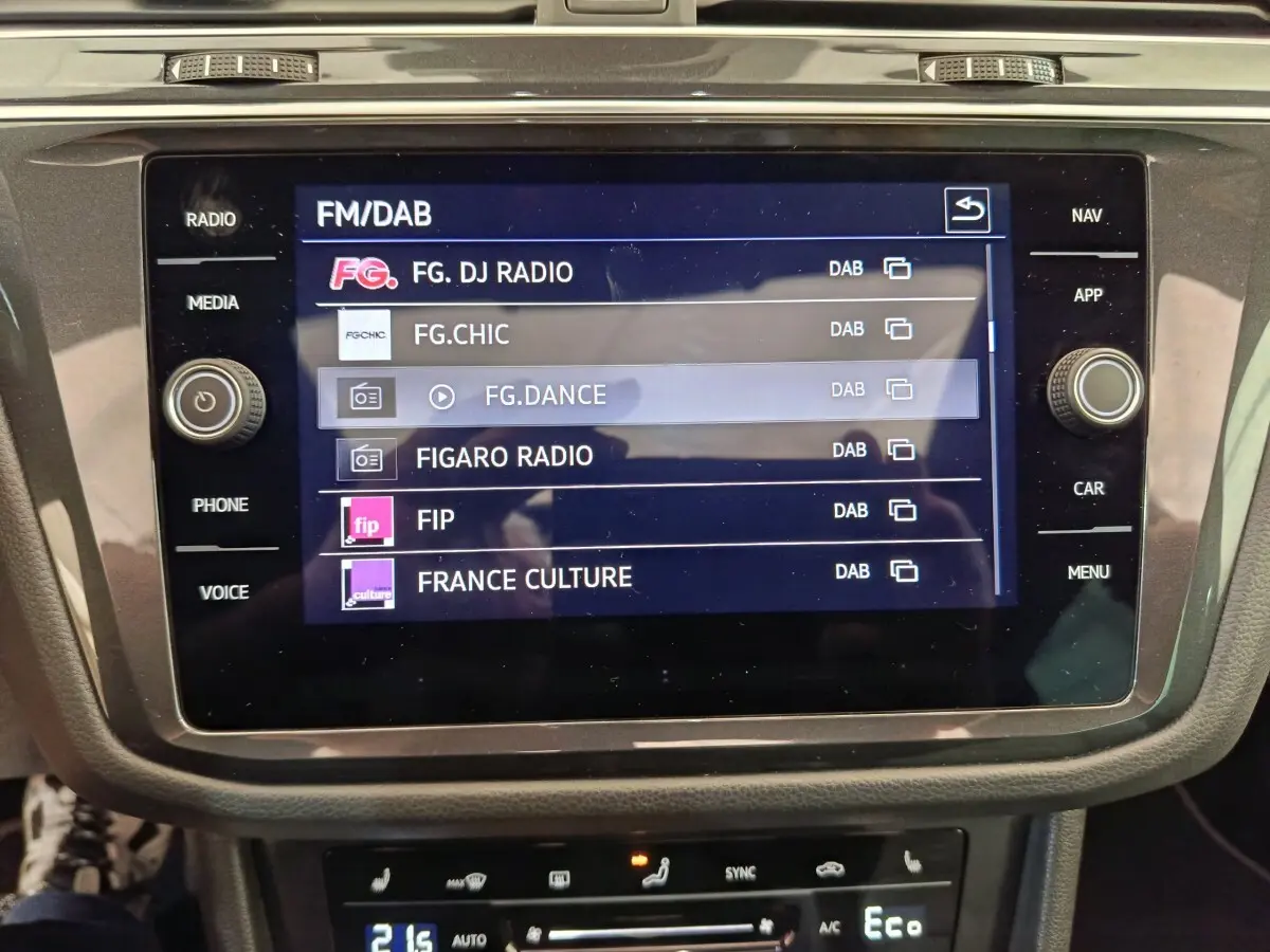 Écran tactile central du Volkswagen Tiguan noir 2023 affichant les stations radio FM/DAB en intérieur.