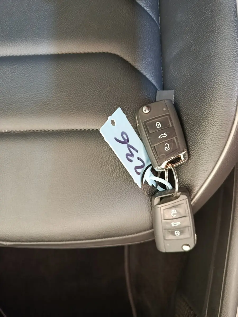 Clé de voiture Volkswagen posée sur un siège en cuir noir à l'intérieur du véhicule, vue rapprochée.