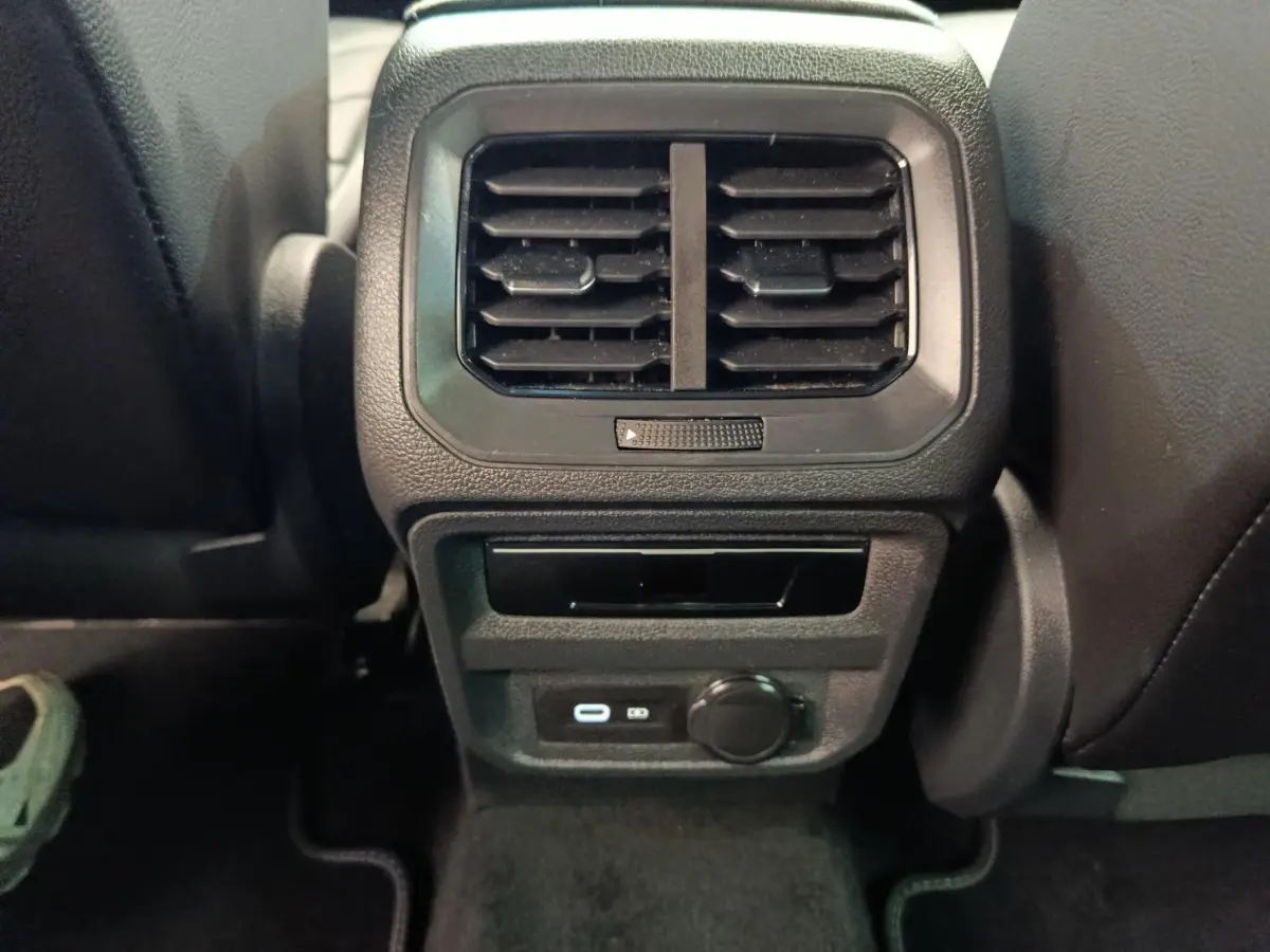 Vue rapprochée de la console arrière noire du Volkswagen Tiguan 2023 avec aérateurs et prises USB visibles.