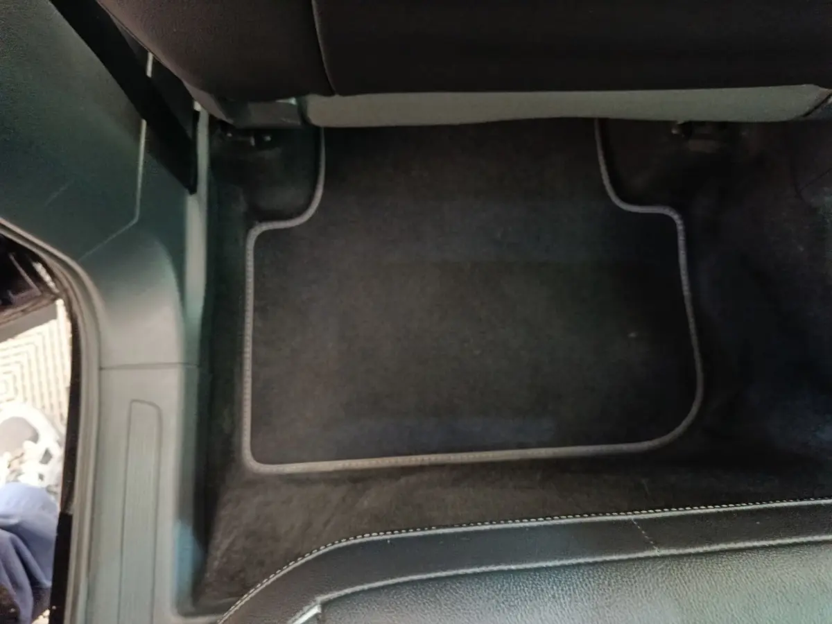 Vue du sol côté passager avant du Volkswagen Tiguan noir 2023, avec tapis de sol et partie inférieure du siège visible.