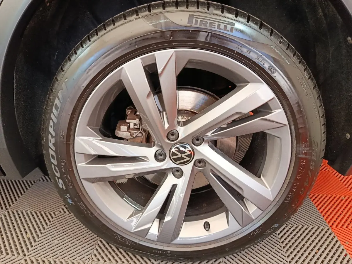 Gros plan sur la roue avant droite du Volkswagen Tiguan noir, avec jante alliage et pneu Pirelli Scorpion.