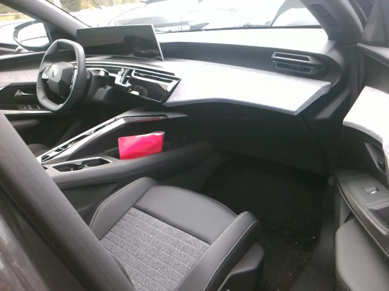 Intérieur du Peugeot 3008 2025 vu côté passager, tableau de bord gris clair et siège tissu noir et gris.