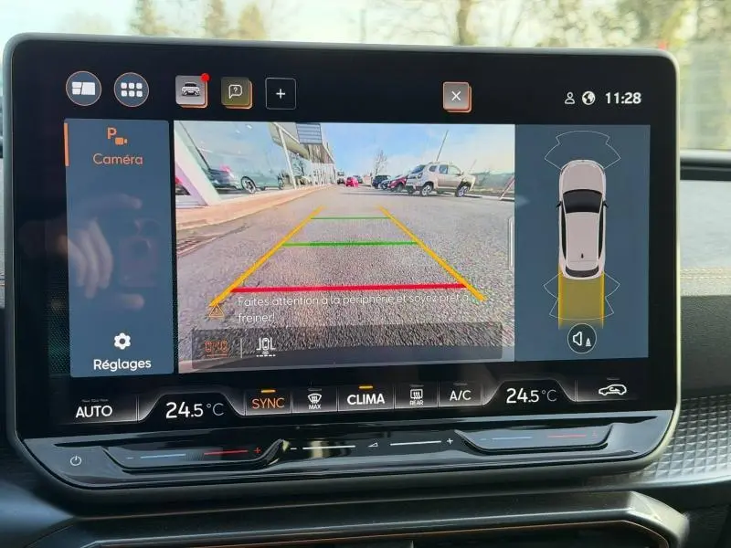 Écran tactile intérieur montrant la caméra de recul et l'interface de stationnement du SEAT LEON gris magnétique, vue frontale.