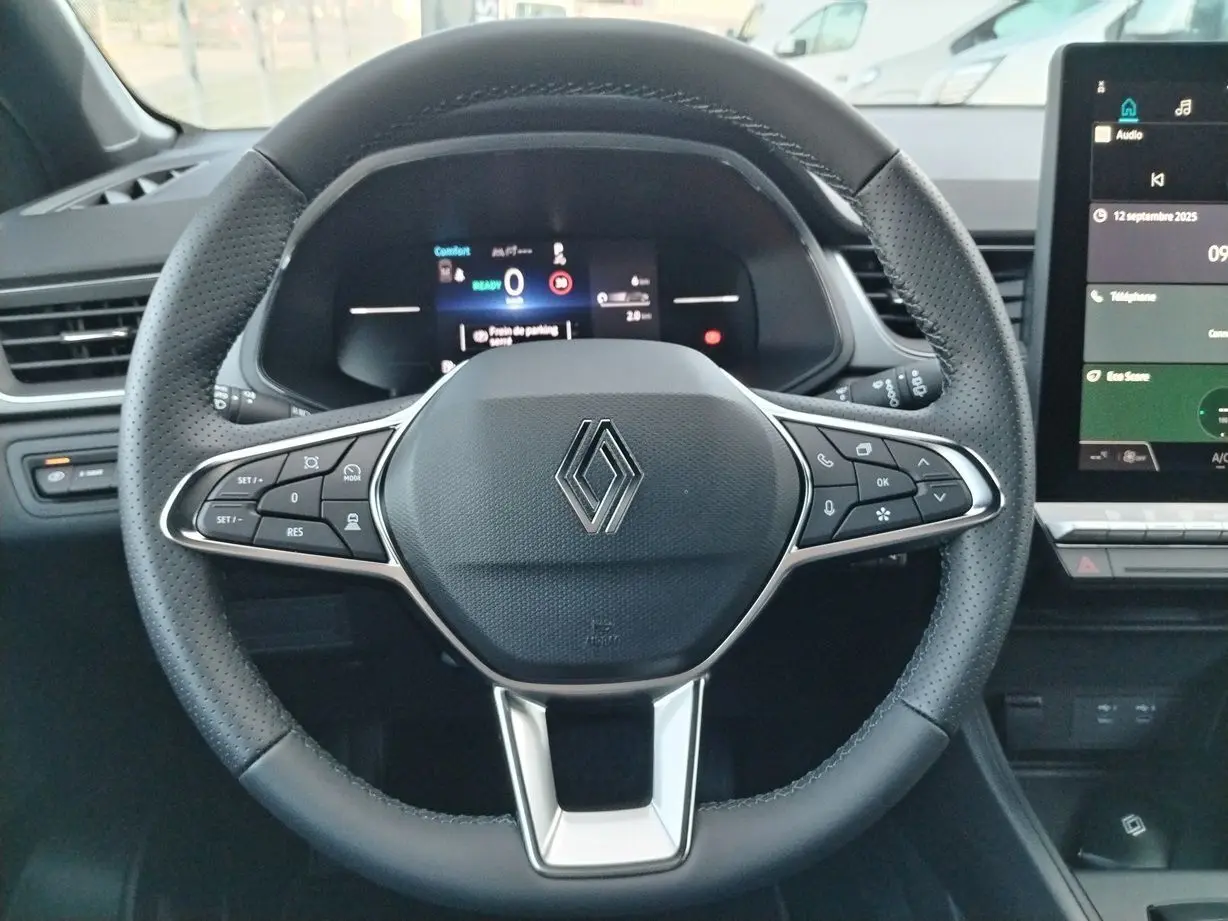 Volant en cuir noir perforé avec logo Renault au centre, tableau de bord numérique et écran tactile à droite.