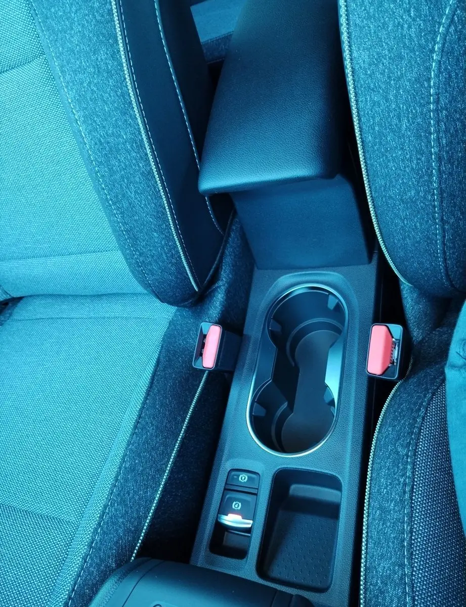 Vue rapprochée de la console centrale avec accoudoir noir et sièges tissu gris du Renault Captur E-Tech 2025.