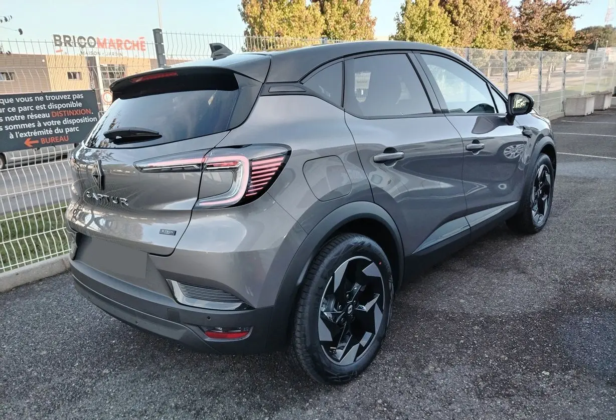 Vue 3/4 arrière droite du Renault Captur E-Tech gris Cassiopée avec toit noir et jantes noires biton.