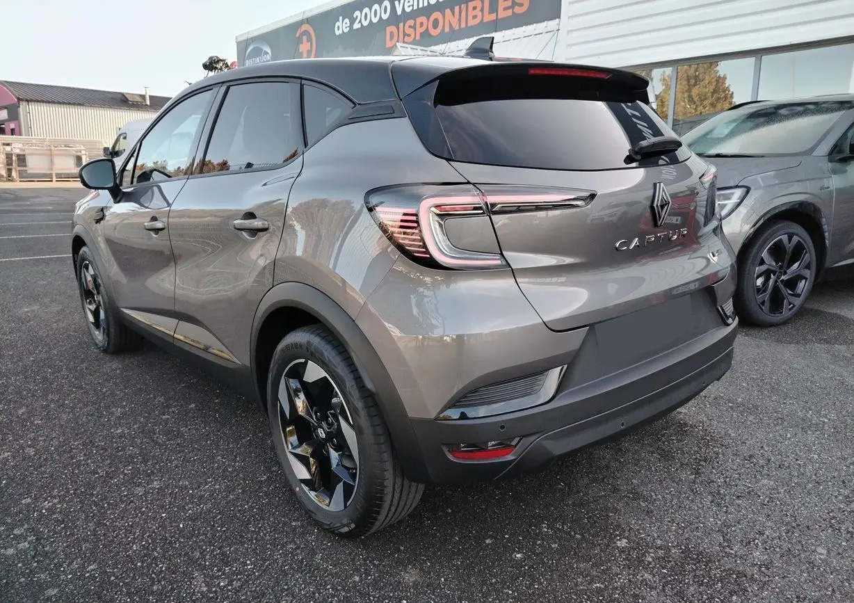 Vue 3/4 arrière gauche d'un Renault Captur gris Cassiopée avec toit noir et jantes noires brillantes.