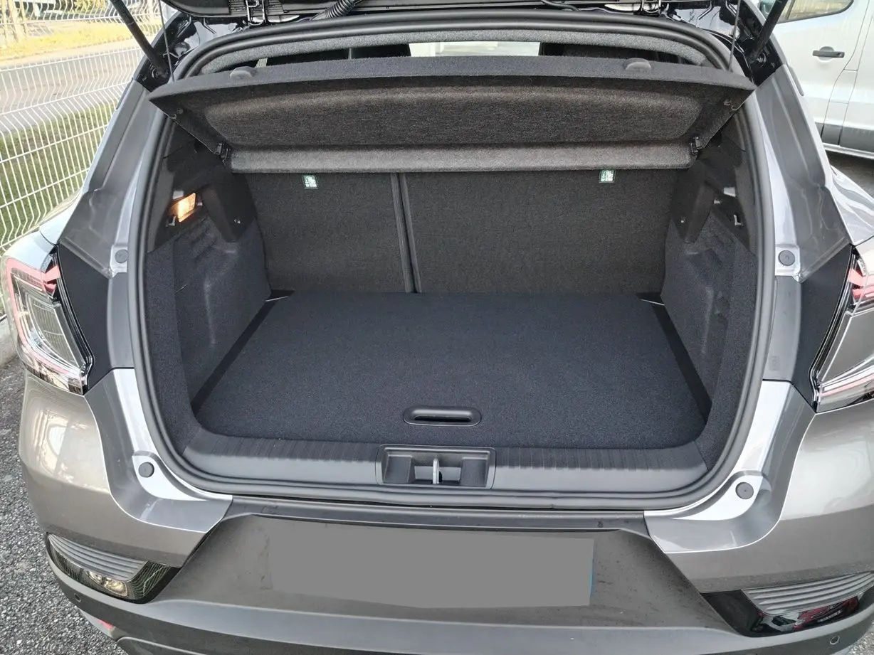 Coffre ouvert vu de l'arrière d'un Renault Captur gris Cassiopée avec toit noir, montrant l'espace de chargement vide.