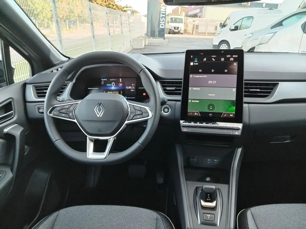 Vue intérieure du tableau de bord du Renault Captur E-Tech 2025, avec volant multifonction et écran tactile central.