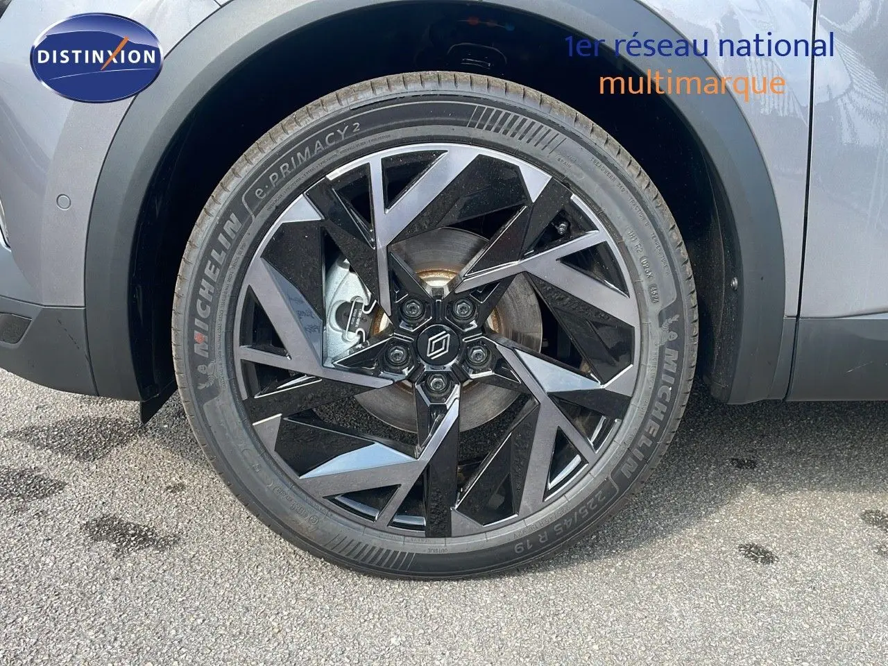 Gros plan sur la roue avant gauche du Renault Captur gris Cassiopée avec jante alliage noire au design géométrique.