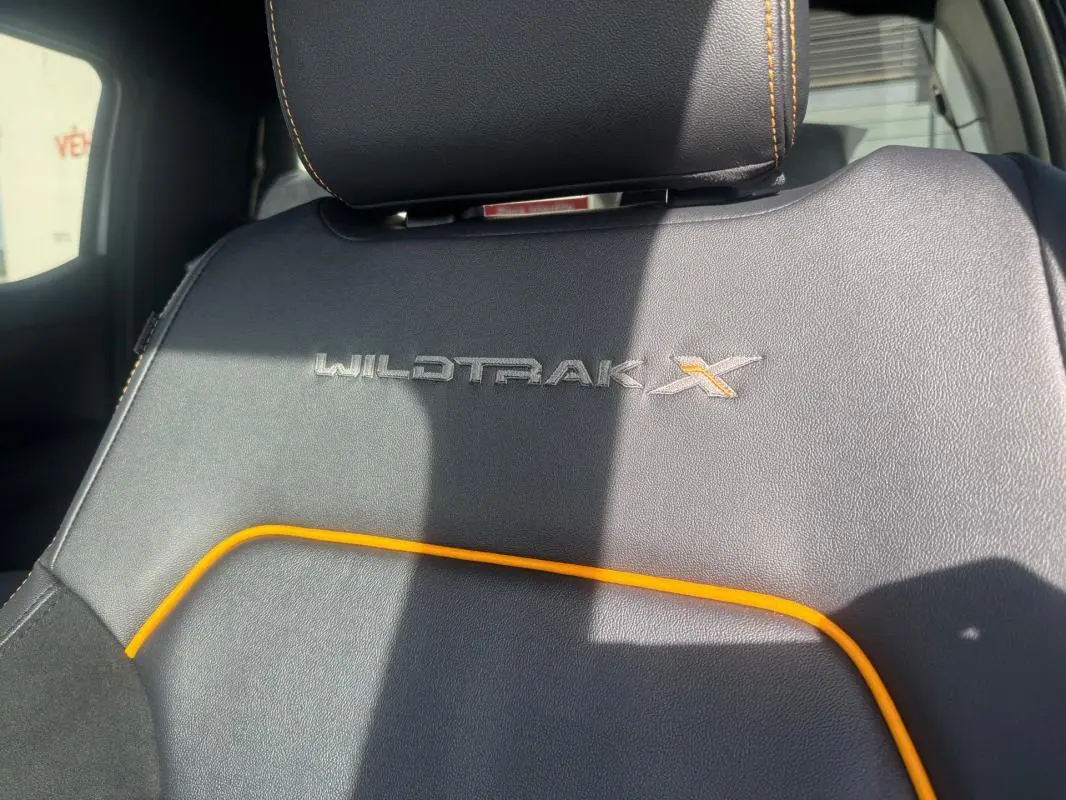 Détail du siège avant en cuir noir avec surpiqûres orange et logo Wildtrak X brodé sur un Ford Ranger gris.