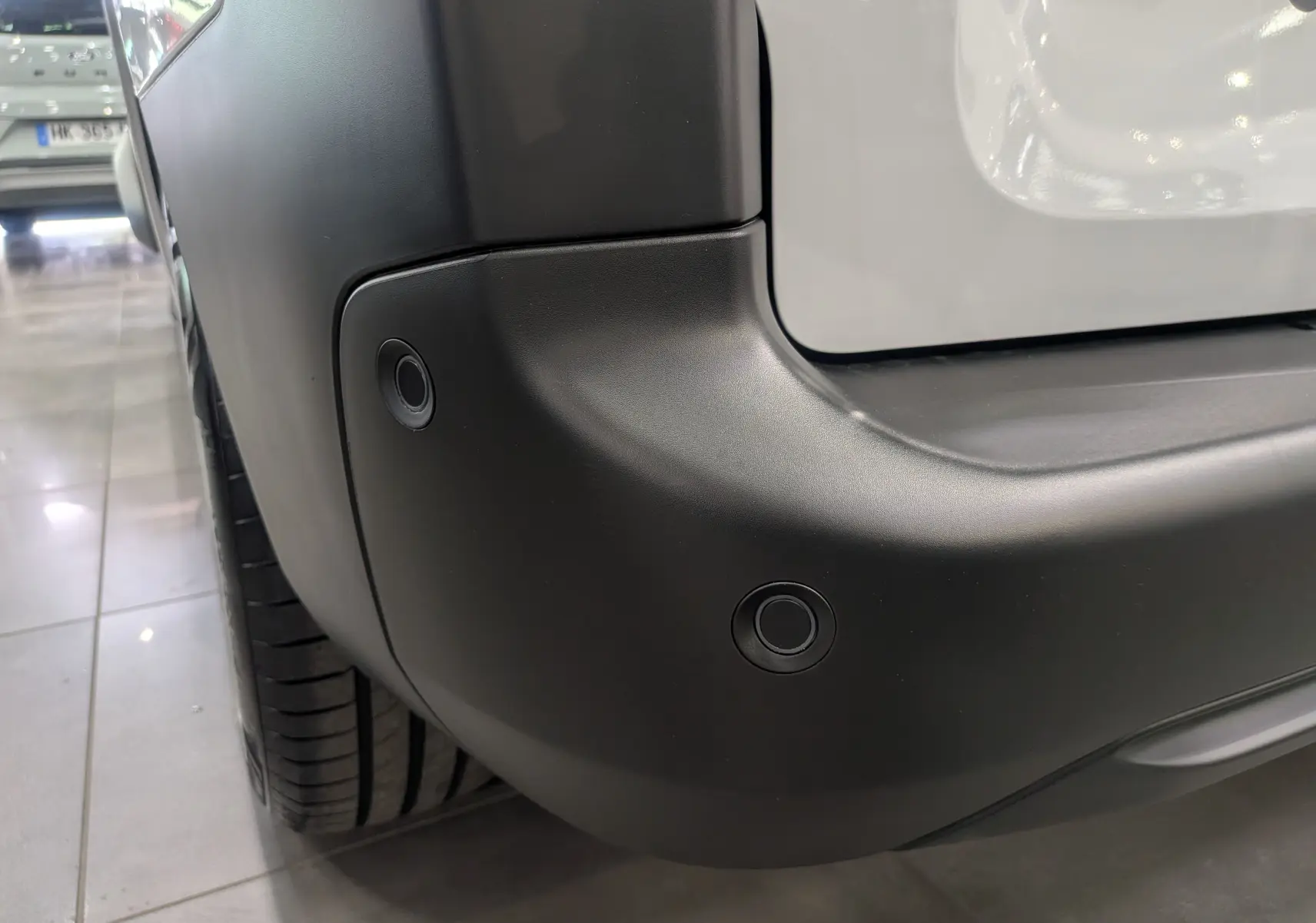 Gros plan sur le pare-chocs arrière noir du Citroën Berlingo blanc 2025, avec capteurs de recul visibles côté gauche.