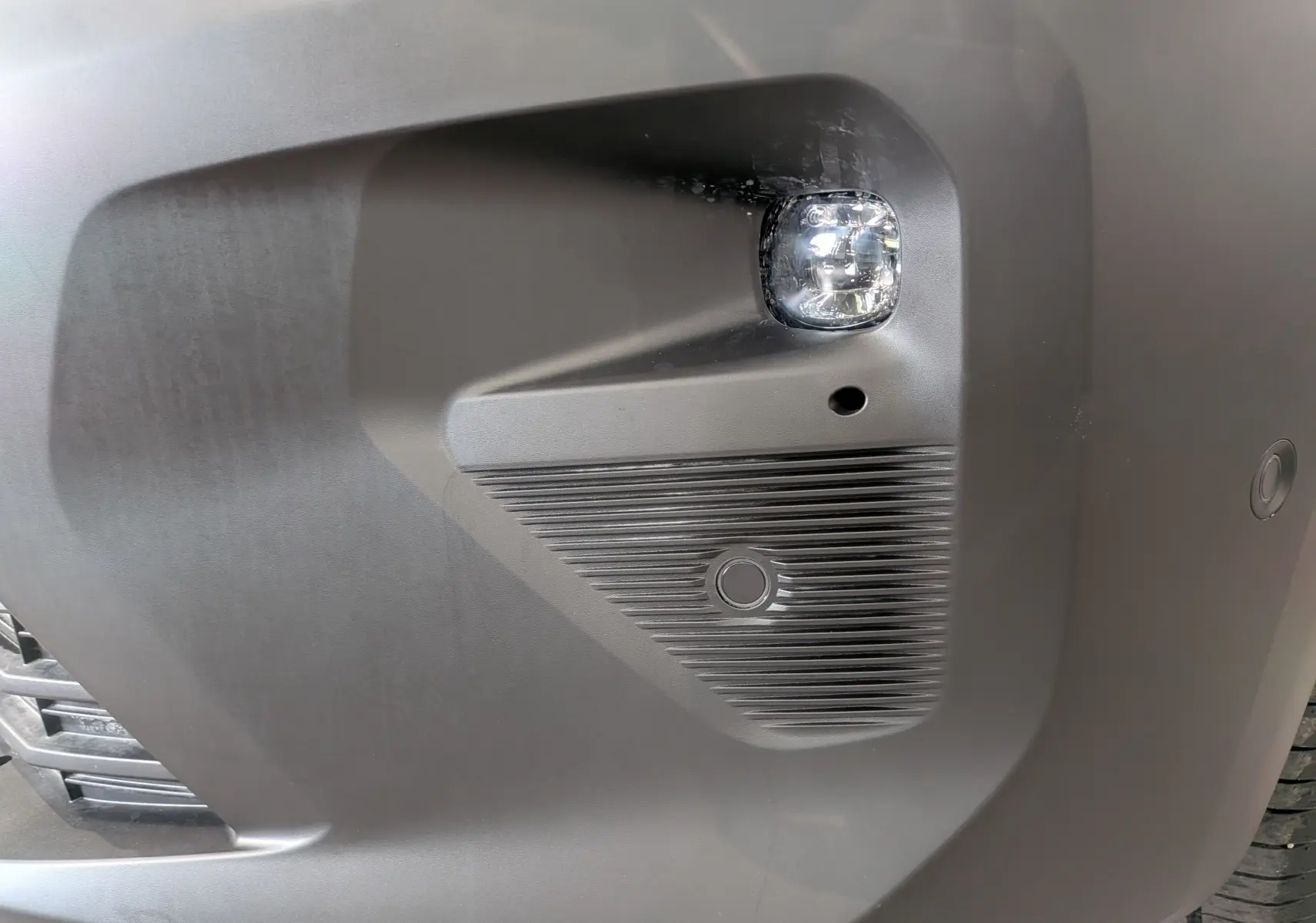 Gros plan sur le pare-chocs avant droit blanc du Citroën Berlingo 2025, avec antibrouillard et capteur de stationnement.