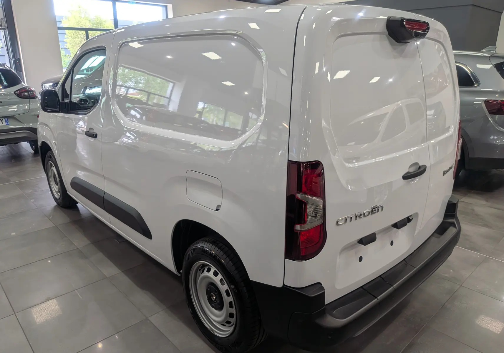 Vue 3/4 arrière droite d'un Citroën Berlingo blanc 2025, fourgon utilitaire avec portes arrière pleines et protections noires.