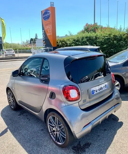Vue 3/4 arrière droite d'une Smart Fortwo Coupé électrique Brabus Style 2019 gris métallisé stationnée en extérieur.
