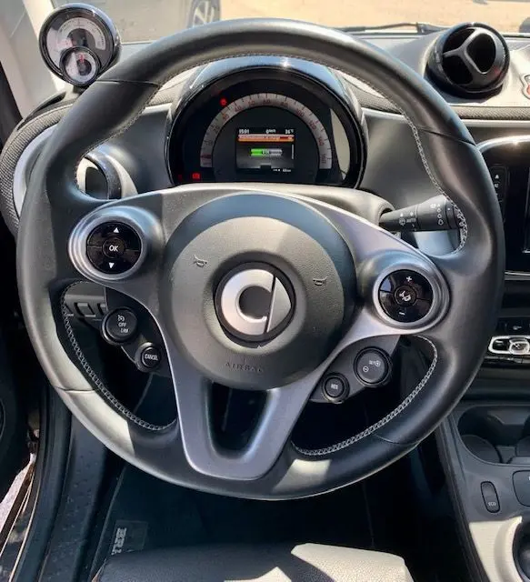 Vue rapprochée du volant et du tableau de bord gris de la Smart Fortwo Electrique Brabus Style 2019 avec commandes intégrées.