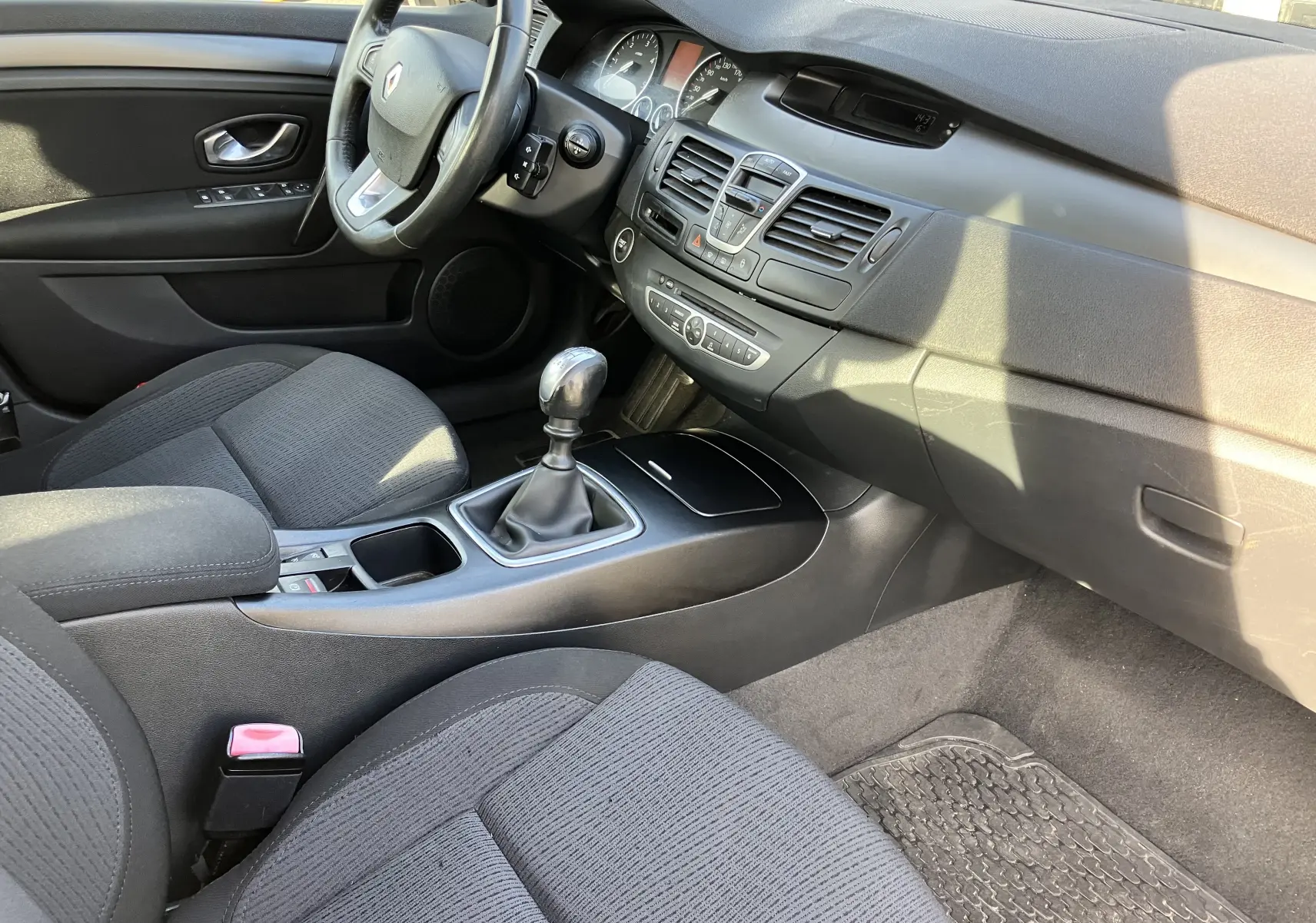 Intérieur noir de Renault Laguna 2008, vue côté conducteur sur tableau de bord et levier de vitesse manuel.