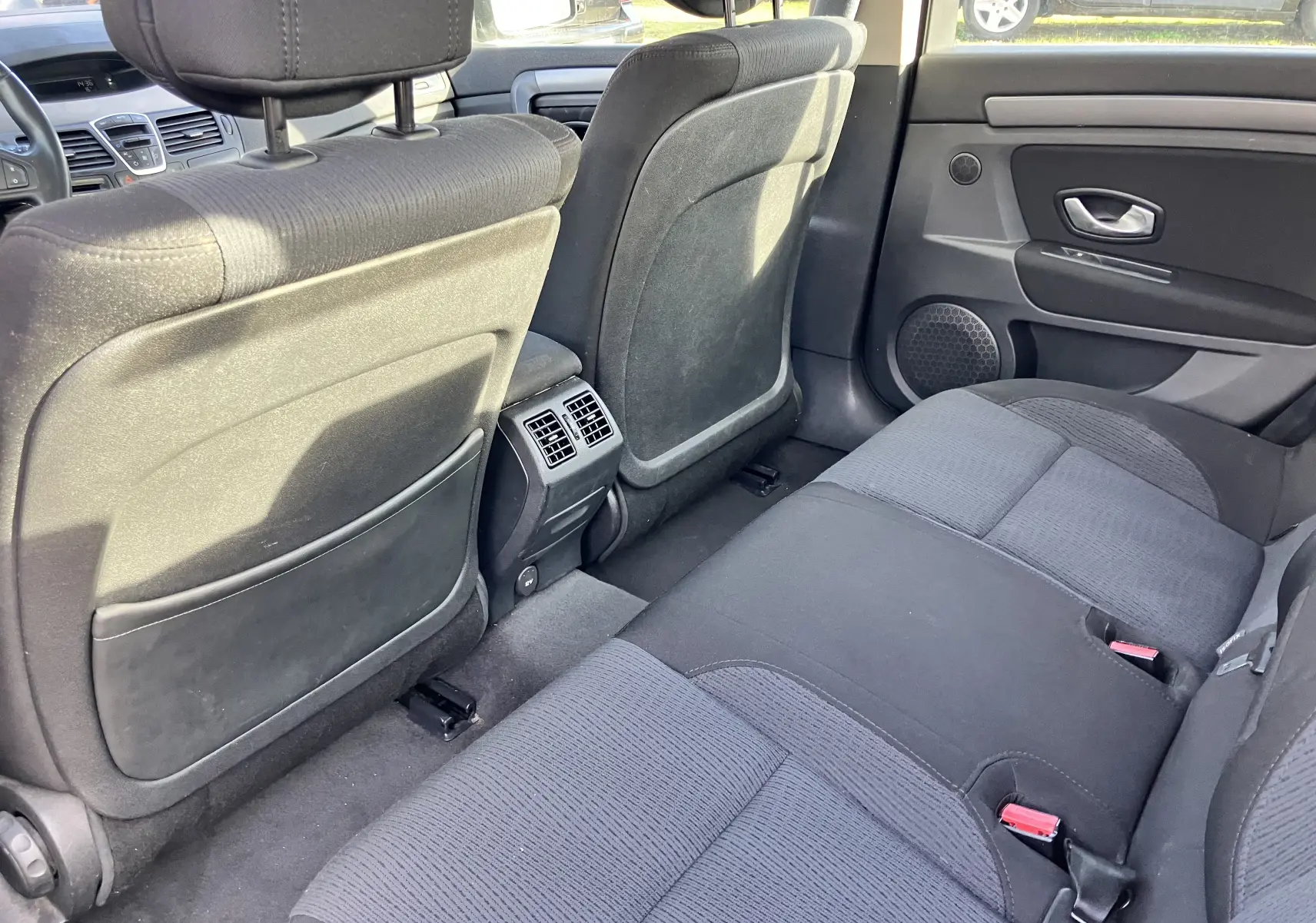 Vue intérieure arrière de la Renault Laguna 2008, sièges tissu noir et aérateurs centraux entre les sièges avant.