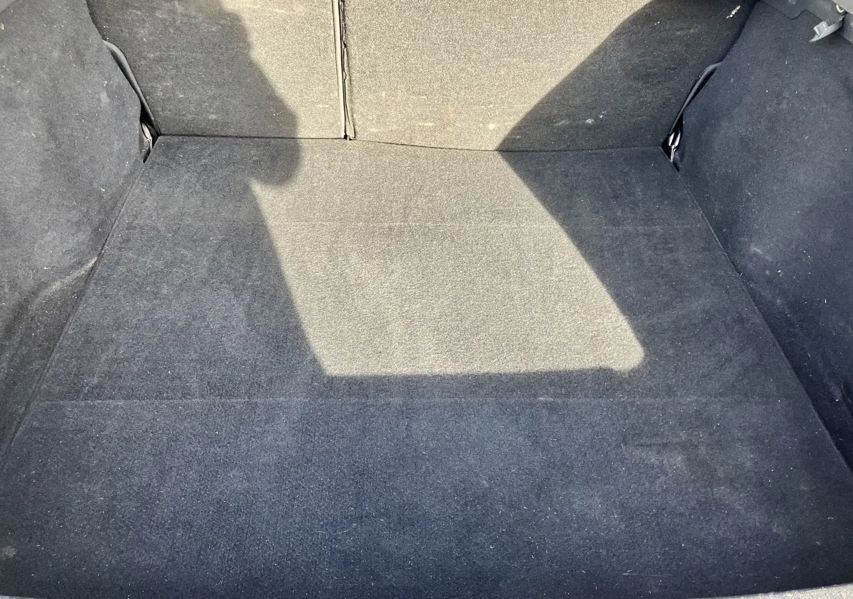 Espace de coffre vide en tissu noir de la Renault Laguna 1.5l dCi 110 ch, vue plongeante intérieure.