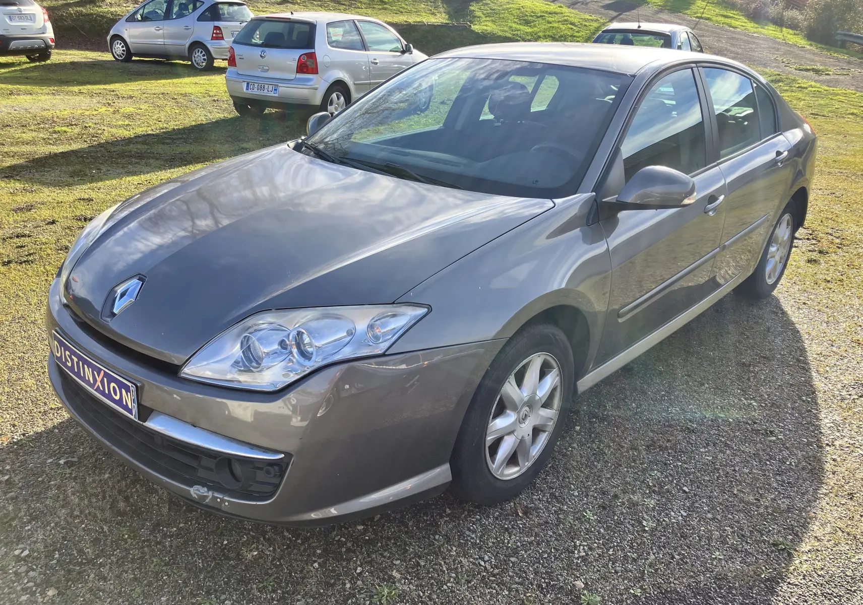 Renault Laguna gris vert 2008 vue 3/4 avant droit, berline 5 portes avec jantes alliage et phares clairs.