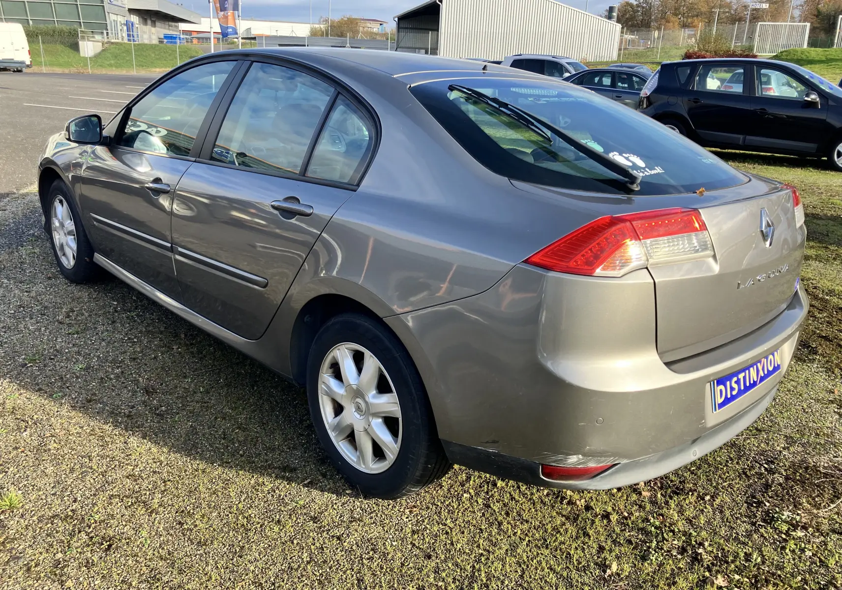 Renault Laguna gris vert vue 3/4 arrière droit, berline 5 portes avec feux arrière distinctifs et jantes alliage.