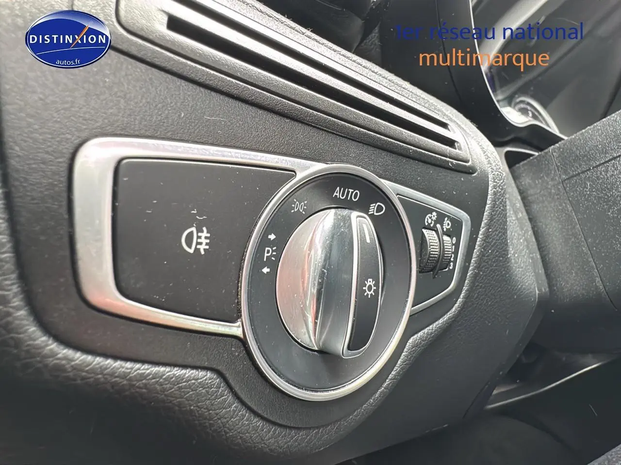 Gros plan sur le sélecteur de phares d'une Mercedes Classe C 180 d business gris alu, intérieur noir texturé.