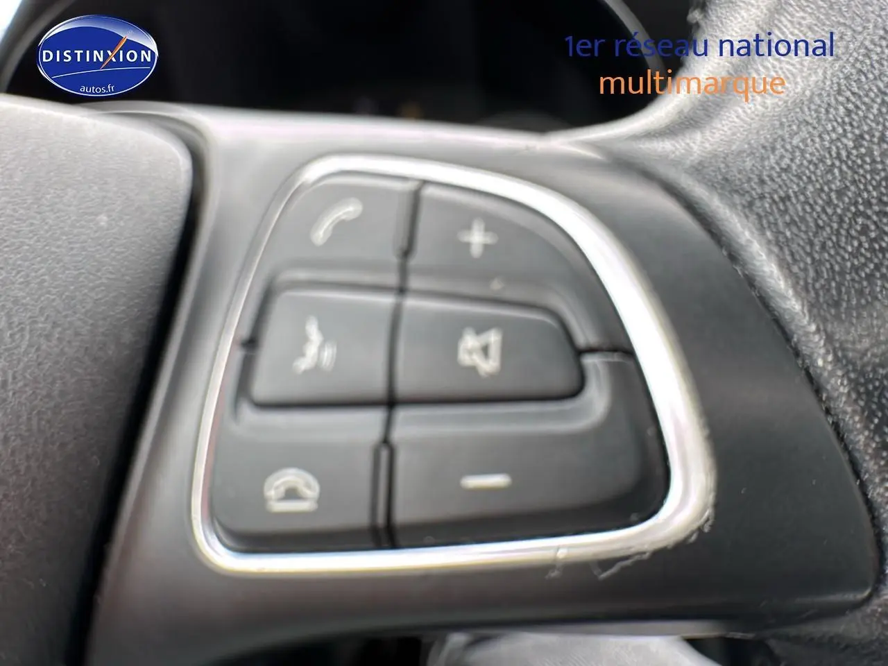 Gros plan sur les commandes multifonctions au volant d'une Mercedes Classe C gris alu de 2017.