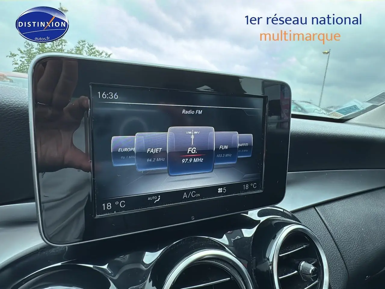 Écran multimédia central affichant la radio FM dans l'habitacle d'une Mercedes Classe C gris alu de 2017.