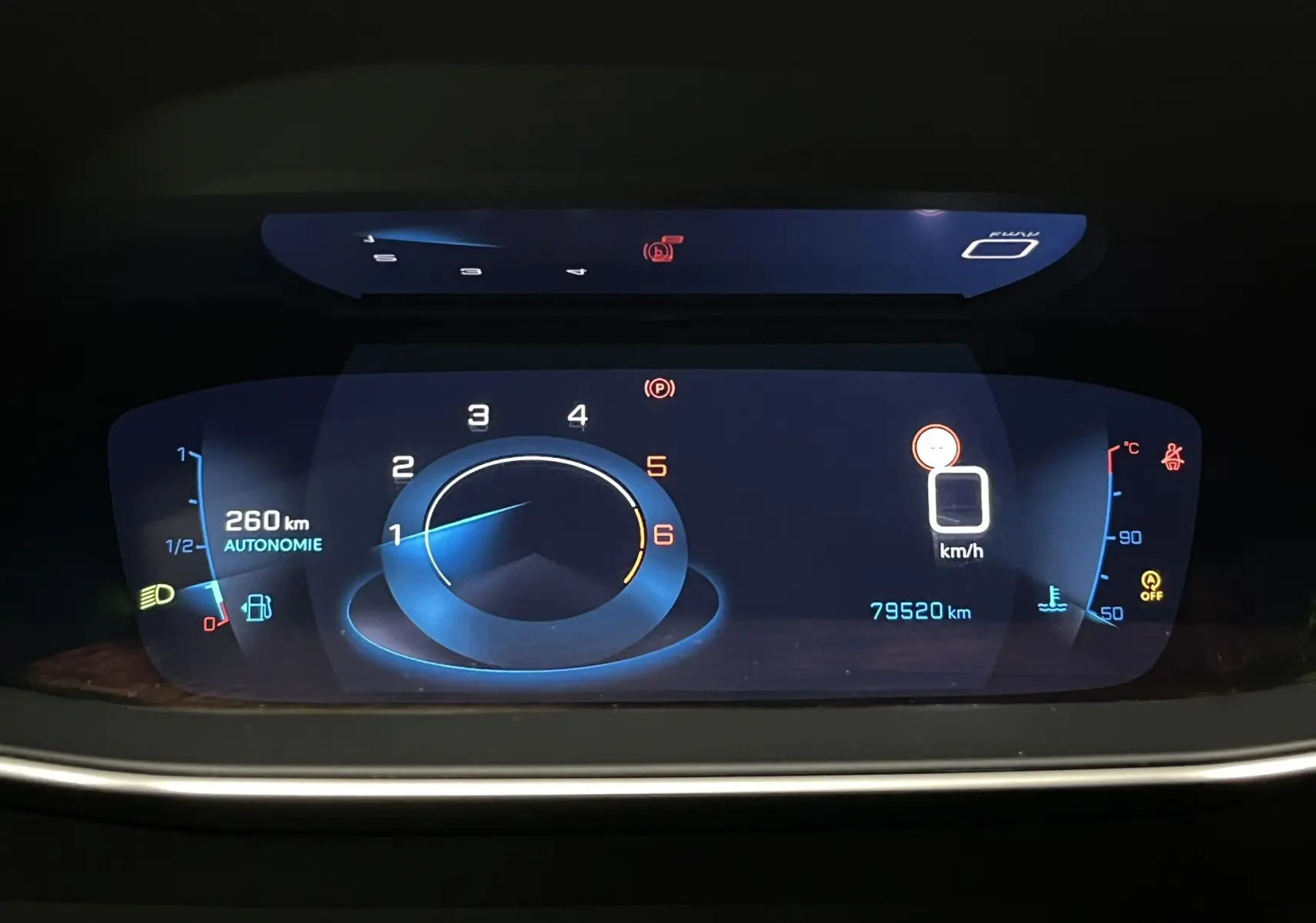 Tableau de bord numérique de Peugeot 208 1.5 BlueHDi, affichant la vitesse, autonomie et compte-tours en vue frontale.