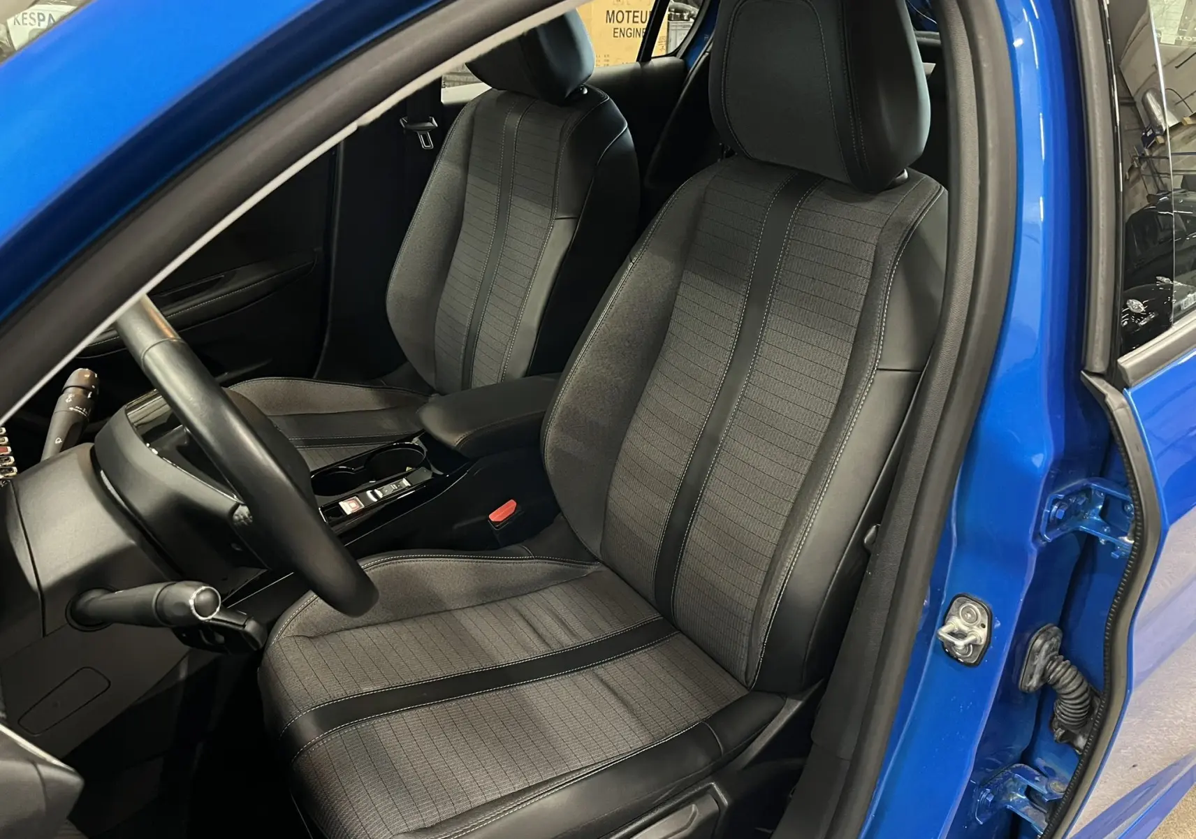 Vue intérieure côté conducteur de la Peugeot 208 1.5 BlueHDi 100 Allure 2020 en Bleu Vertigo, sièges tissu gris et cuir noir.