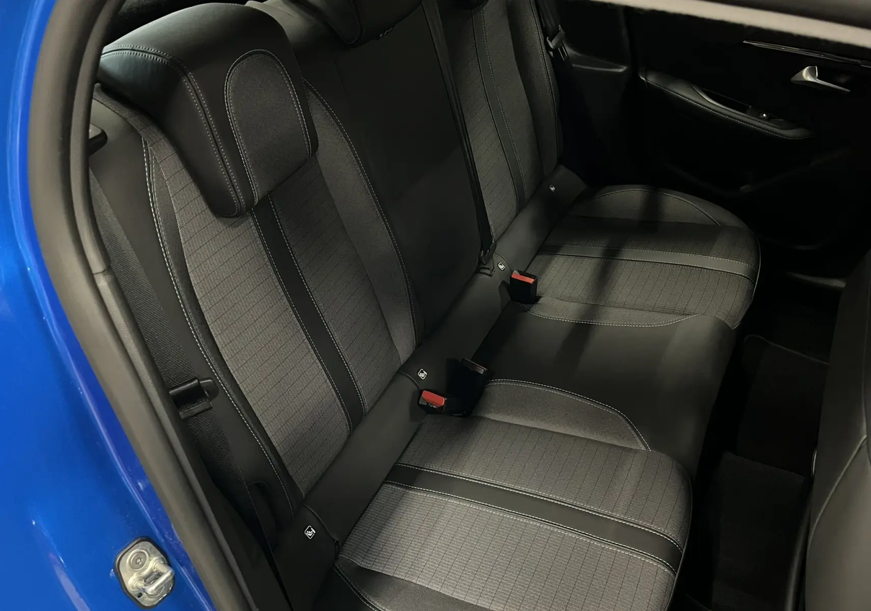 Vue intérieure côté gauche des sièges arrière gris foncé de la Peugeot 208 Bleu Vertigo avec ceinture et porte ouvert.