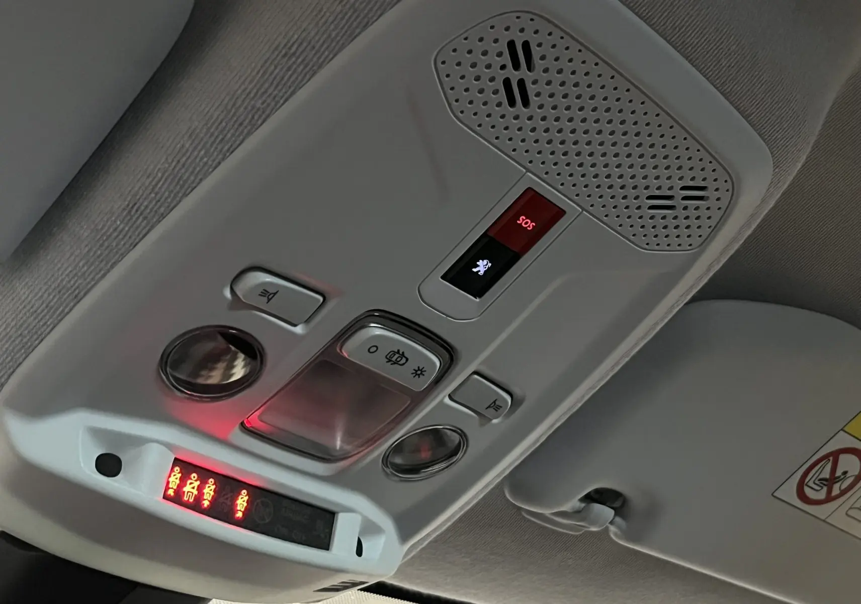 Vue intérieure du plafonnier de la Peugeot 208 2020 Bleu Vertigo avec boutons d’éclairage et alerte SOS allumée.