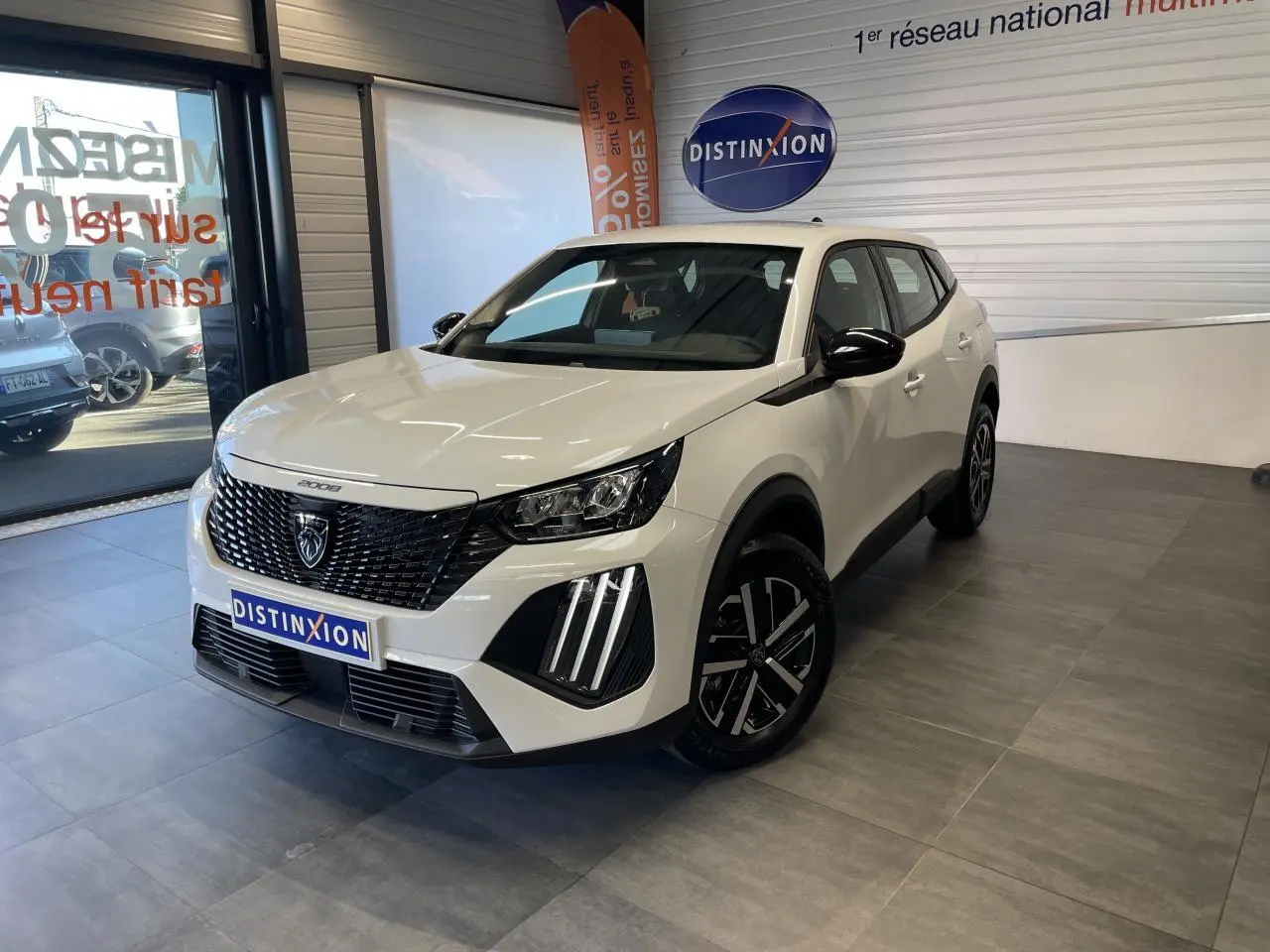Peugeot 2008 blanc vue 3/4 avant droit en showroom, avec calandre noire et feux LED griffés.