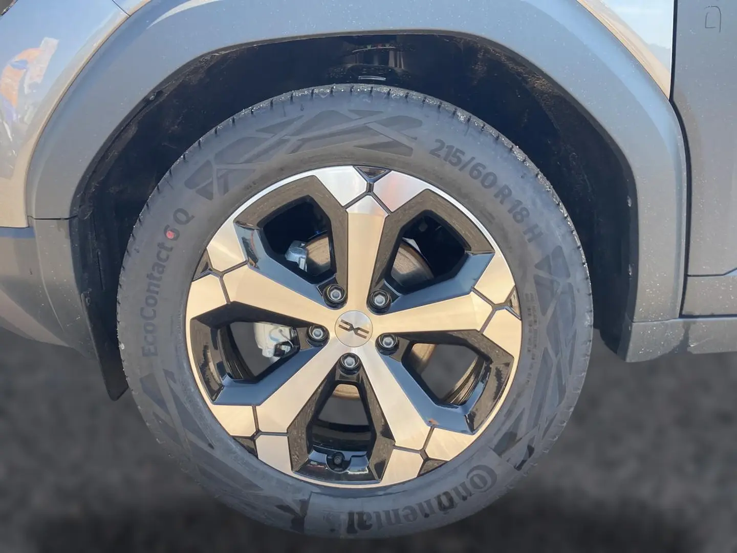 Gros plan sur la roue avant droite du Dacia Duster gris schiste, mettant en valeur la jante alu au design géométrique.