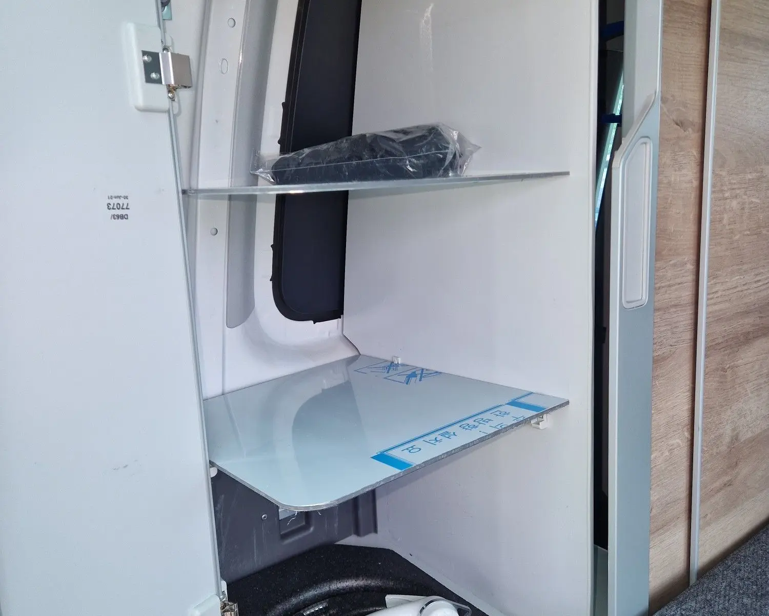 Intérieur du Volkswagen California 2021 Cooper bronze montrant un rangement avec douchette escamotable et étagères blanches.