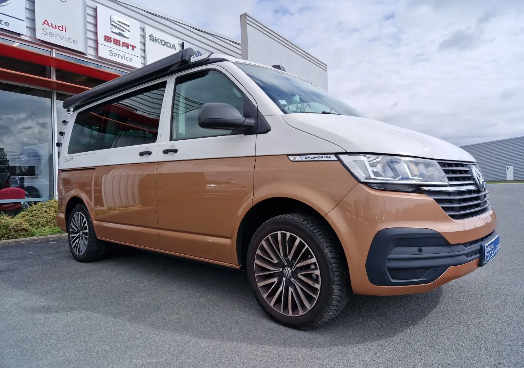 Vue 3/4 avant droite du Volkswagen California Cooper bronze 2021 avec toit relevable et jantes alliage distinctives.