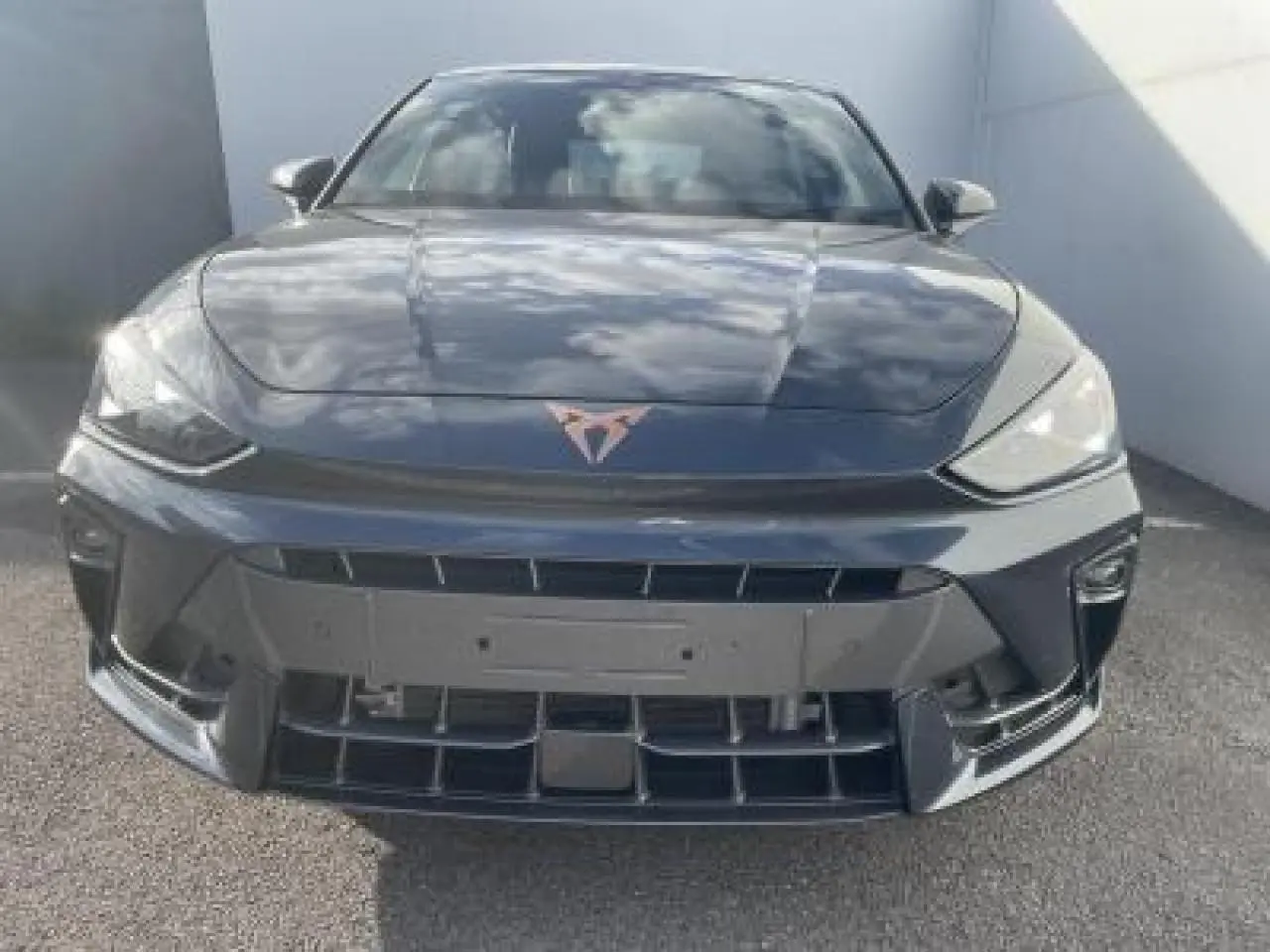 Vue avant d'une CUPRA Leon 2025 gris magnetic metal avec logo CUPRA cuivré et phares LED triangulaires.