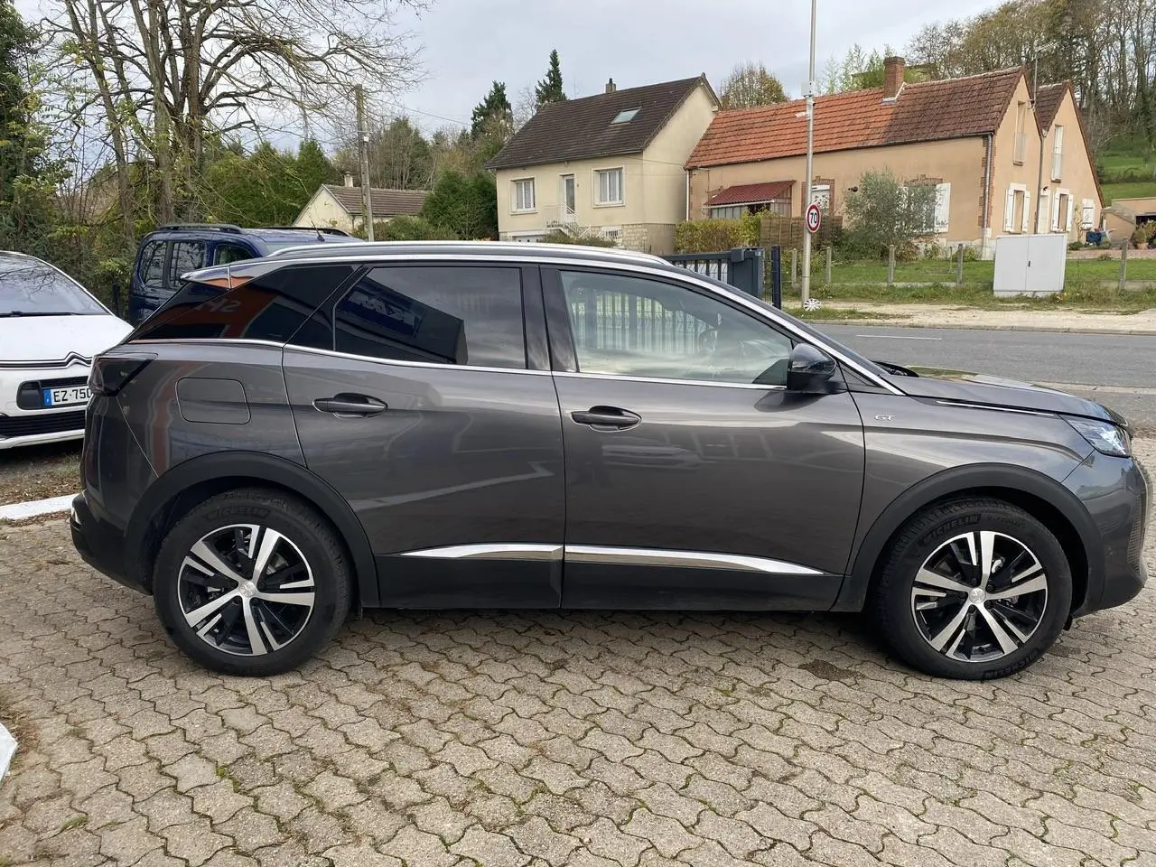 Profil côté gauche d'un Peugeot 3008 gris foncé 2023 avec jantes alliage et coques de rétroviseurs noires.