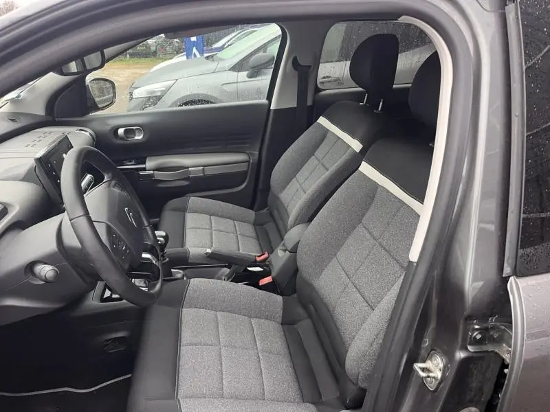 Vue intérieure côté conducteur de la Citroën C4 Cactus gris Platinium avec sièges tissu gris à bandes claires.