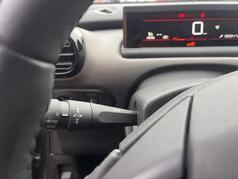 Gros plan sur la manette de commande des phares à gauche du volant dans l'habitacle gris du Citroën C4 Cactus 2020.