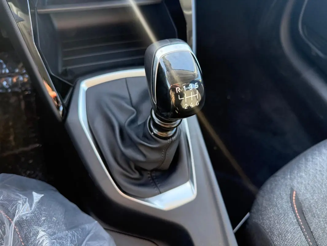 Gros plan sur le levier de vitesse manuel noir de la Peugeot 208 100 S&S BVM6 Style, intérieur tissu gris.