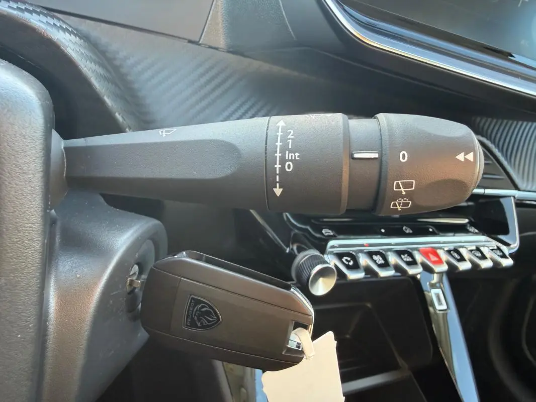 Gros plan sur la commande d’essuie-glace et la clé insérée dans le contact d’une Peugeot 208 jaune 2025.