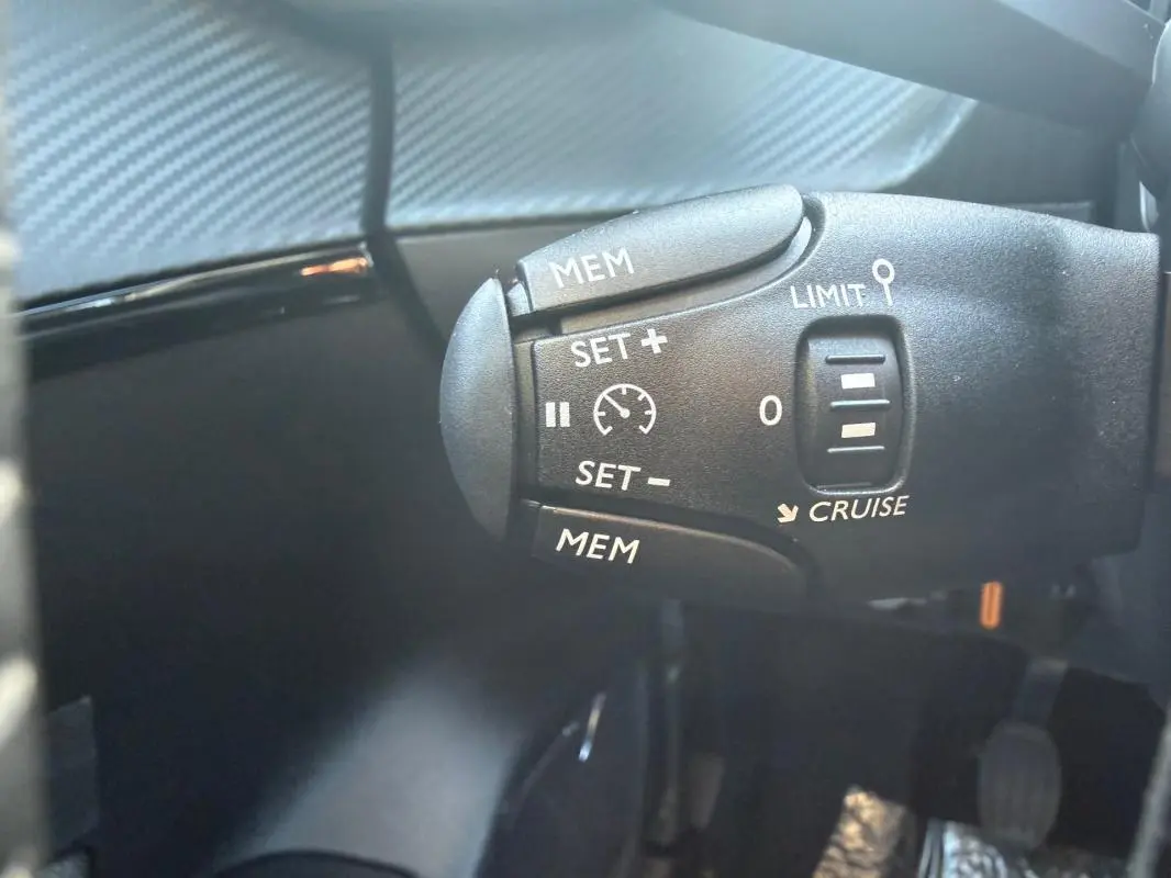Gros plan sur la commande de régulateur de vitesse dans l'habitacle d'une Peugeot 208 jaune 2025.
