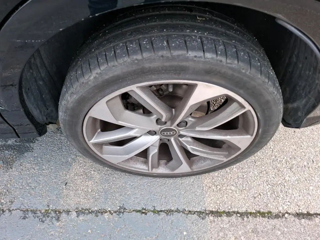 Gros plan sur la jante alu 19 pouces en Y de couleur grise d'un Audi Q2 noir, vue côté droit.